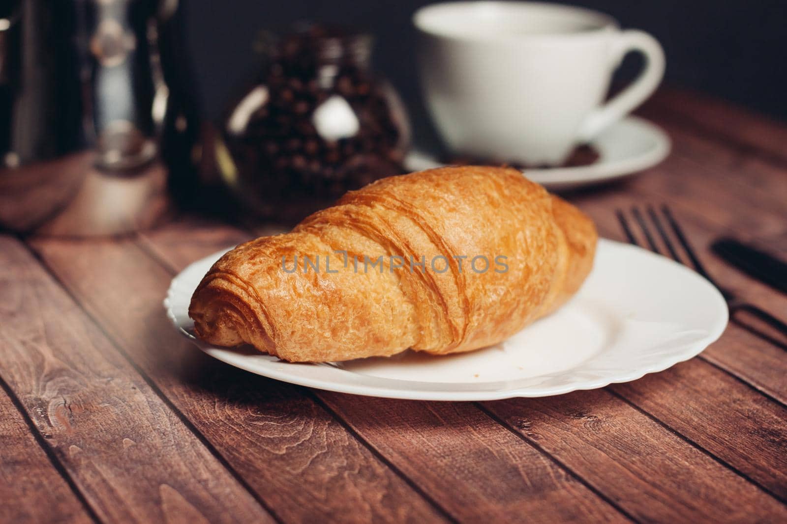 croissants saucer on the table fork with a knife fresh pastries. High quality photo