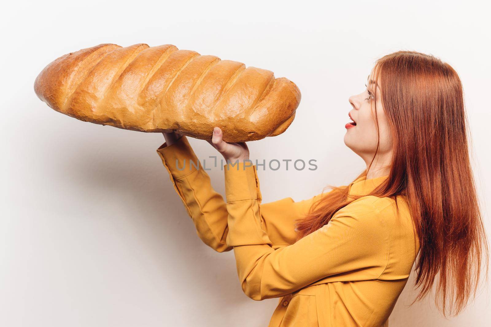 woman in a yellow shirt with a huge loaf in her hands a flour product light background. High quality photo