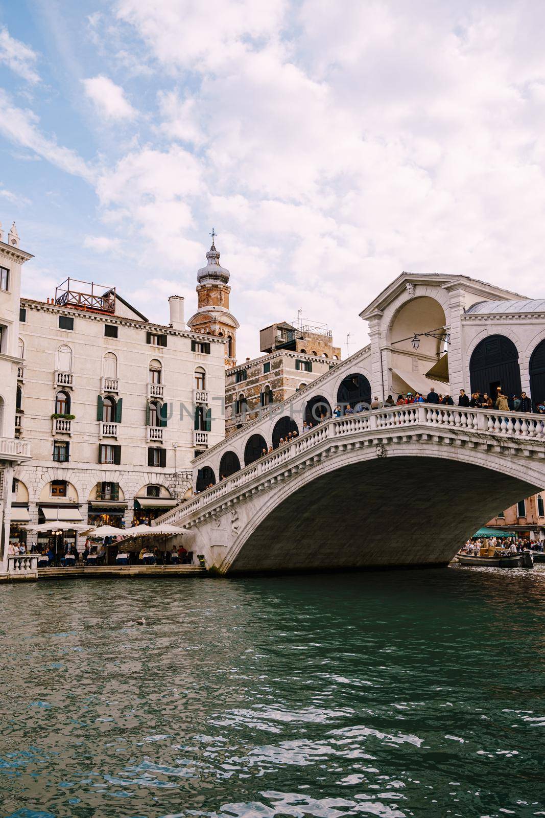 The beautiful Ponte di Rialto Bridge over Central Grand Canal in Venice, Italy, with shops, beautiful views and lots of people. Near boat station of the same name, the street leads to San Marco