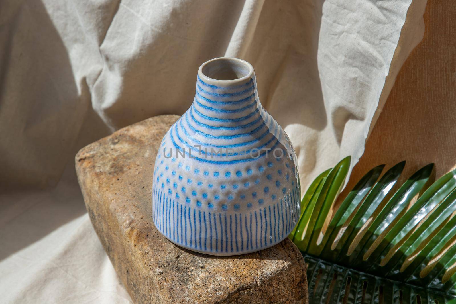 White and Blue handmade ceramic vase on white textured table cloth.  Home decor, Copy space, Selective focus.