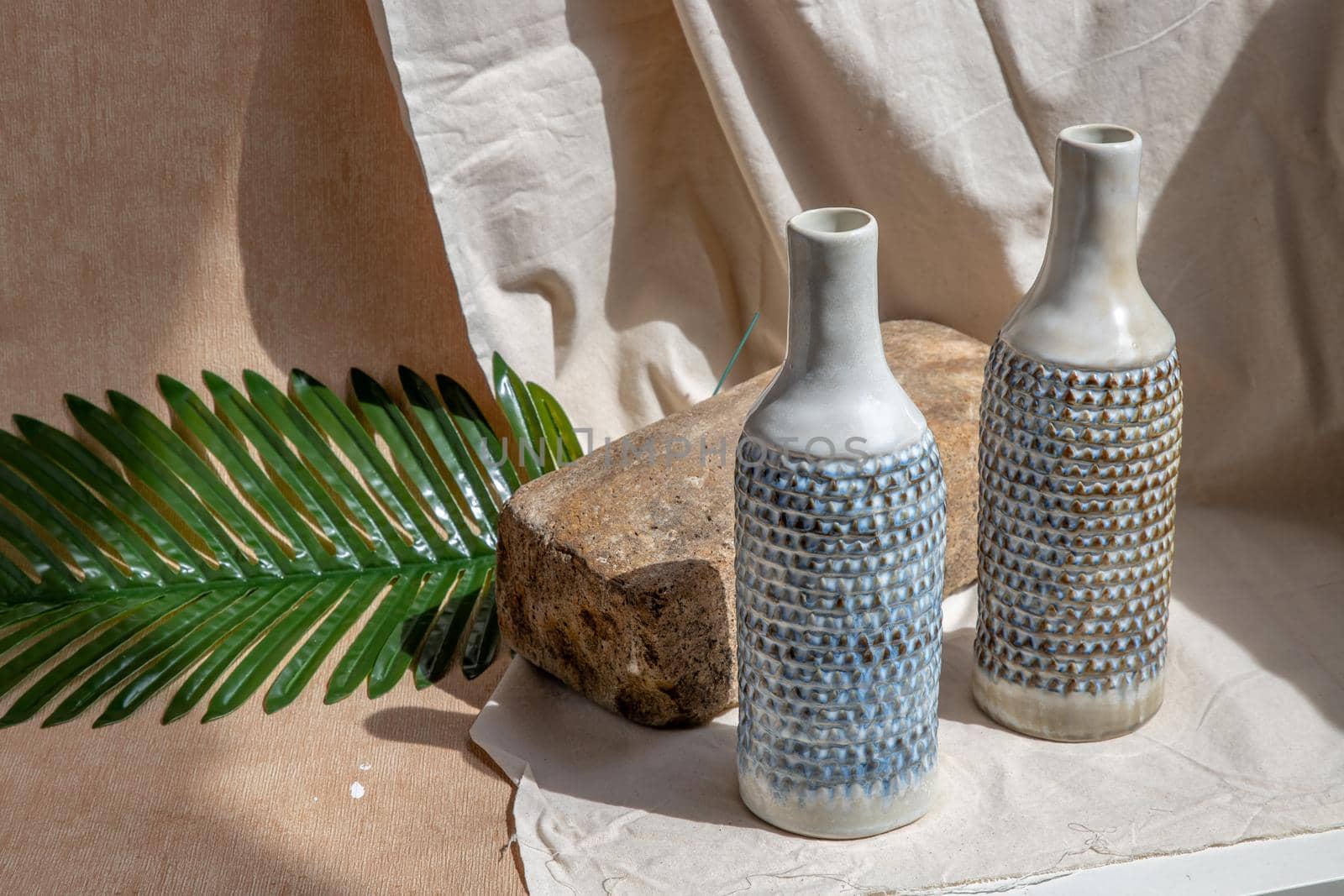 Two white and blue handmade ceramic vases on white textured table cloth.  Home decor, Copy space, Selective focus.