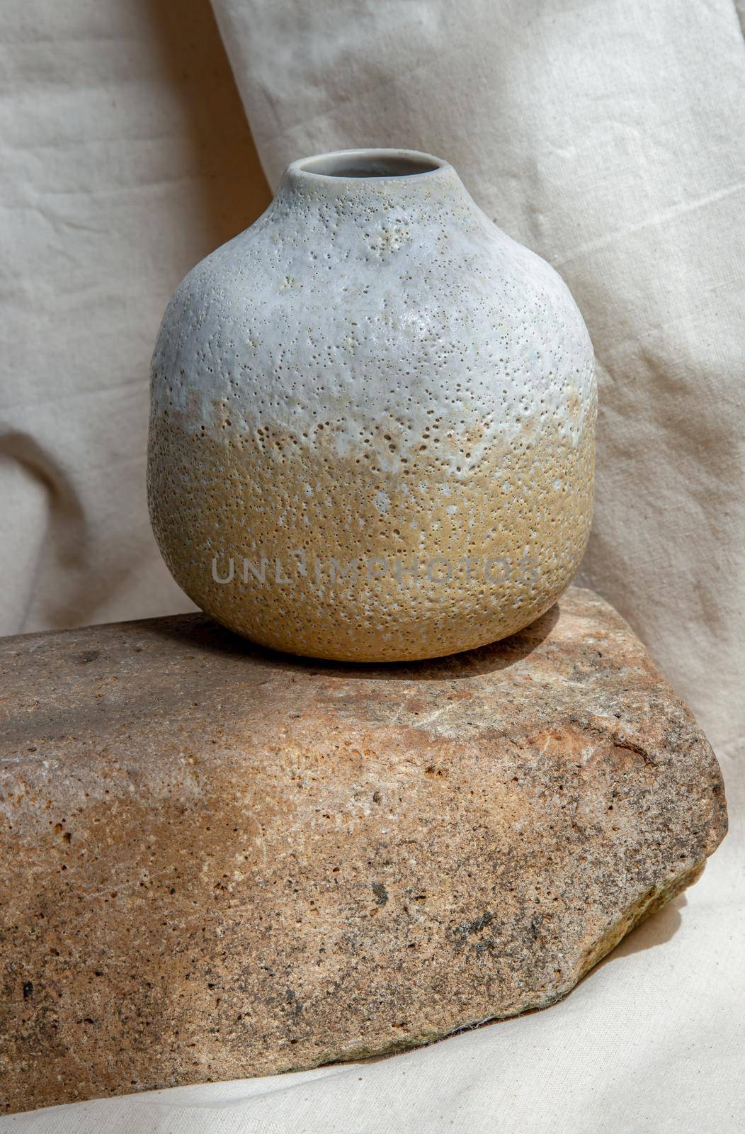 White and Yellow handmade ceramic vase on white textured table cloth. Home decor, Copy space, Selective focus.