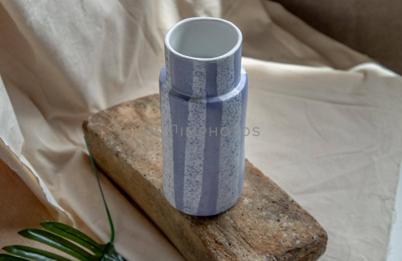 Blue handmade ceramic vase on white textured table cloth. Home decor, Copy space, Selective focus.