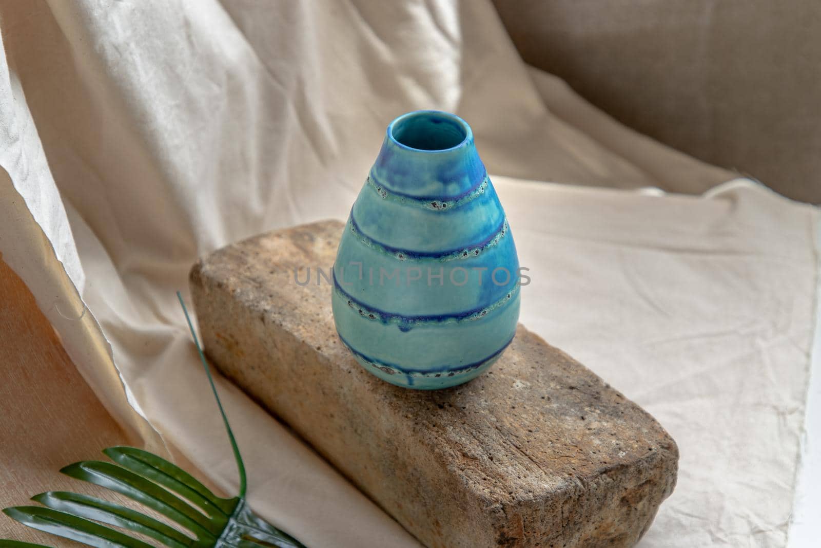 Blue handmade ceramic vase on white textured table cloth. Home decor, Copy space, Selective focus.