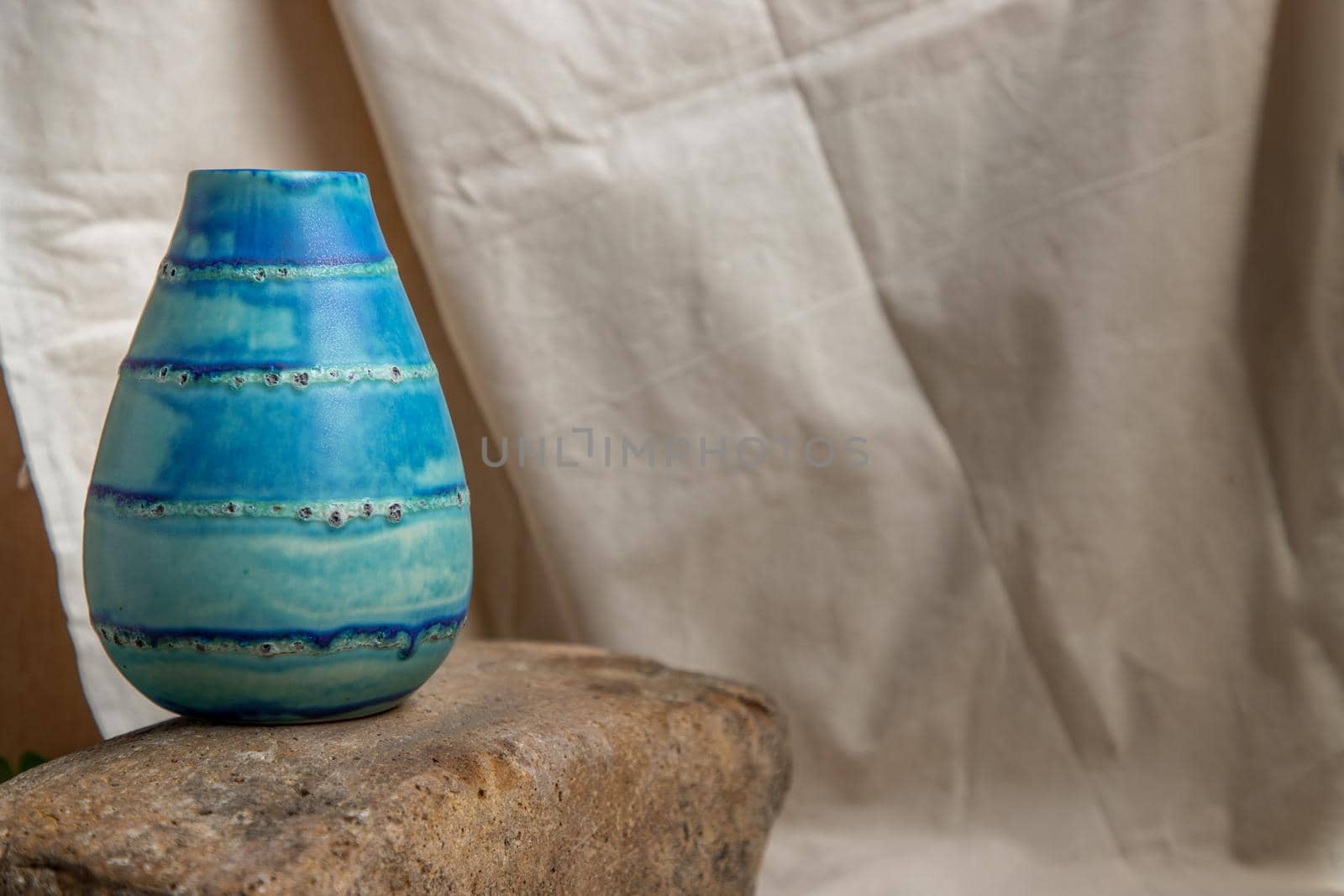 Blue handmade ceramic vase on white textured table cloth. Home decor, Copy space, Selective focus.