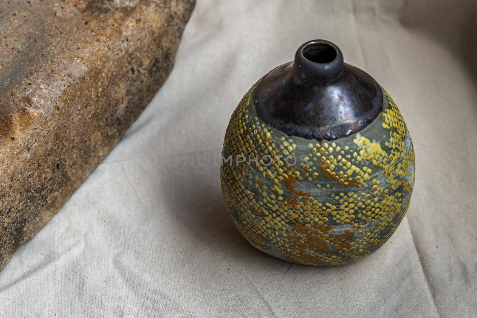 Yellow handmade ceramic vase on white textured table cloth. Home decor, Copy space, Selective focus.