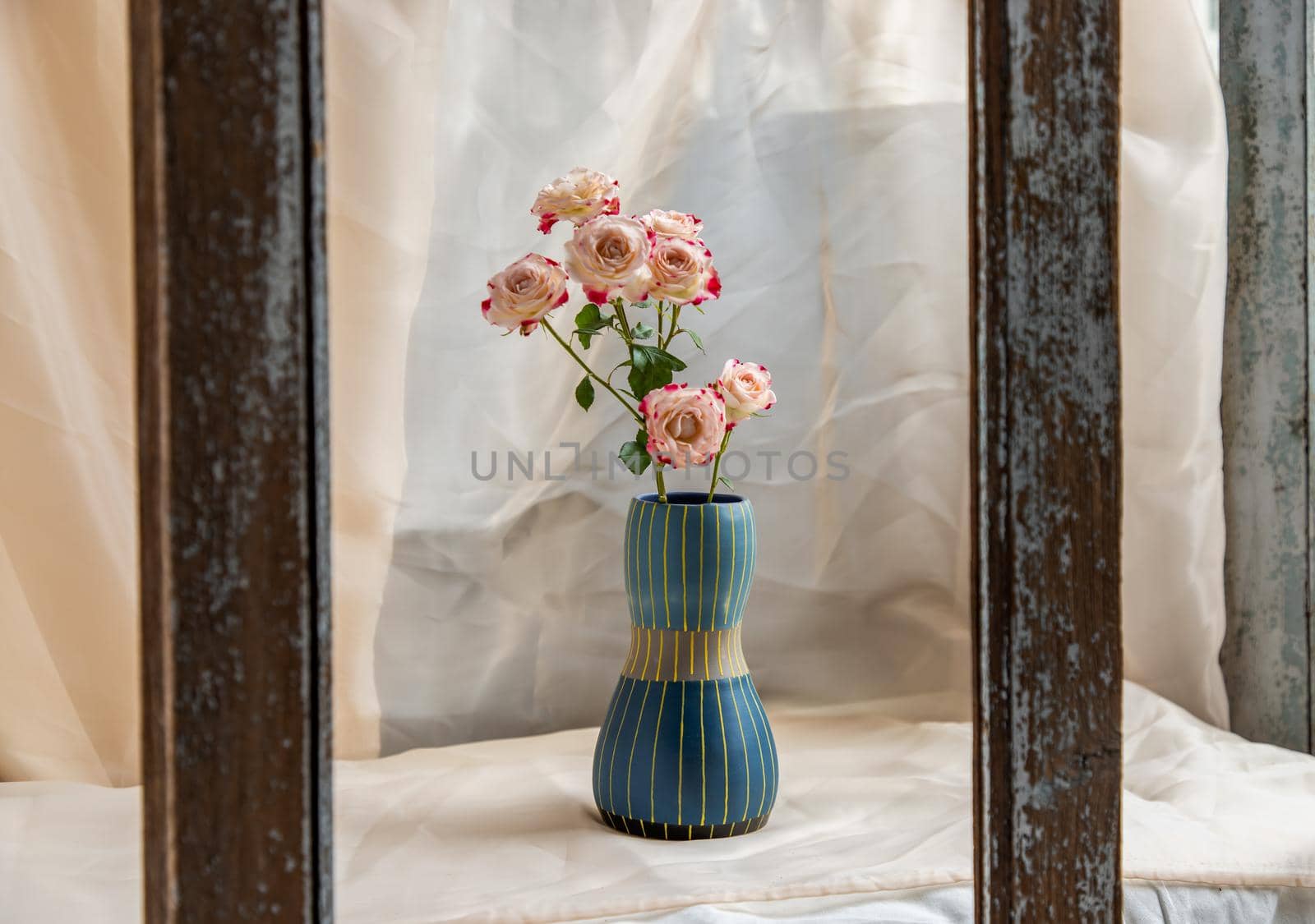 Bouquet of flower in Blue handmade ceramic vase on Blush textured table cloth. Home decor, Copy space, Selective focus.