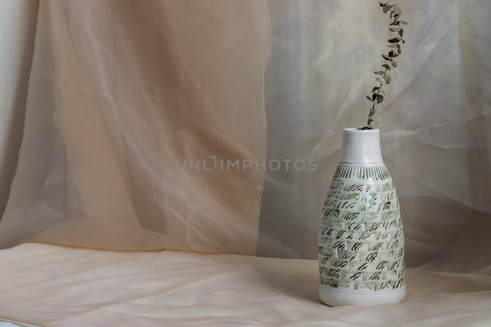 Dried flowers in White ceramic vase bottle shape on Blush textured table cloth. Home decor, Copy space, Selective focus.