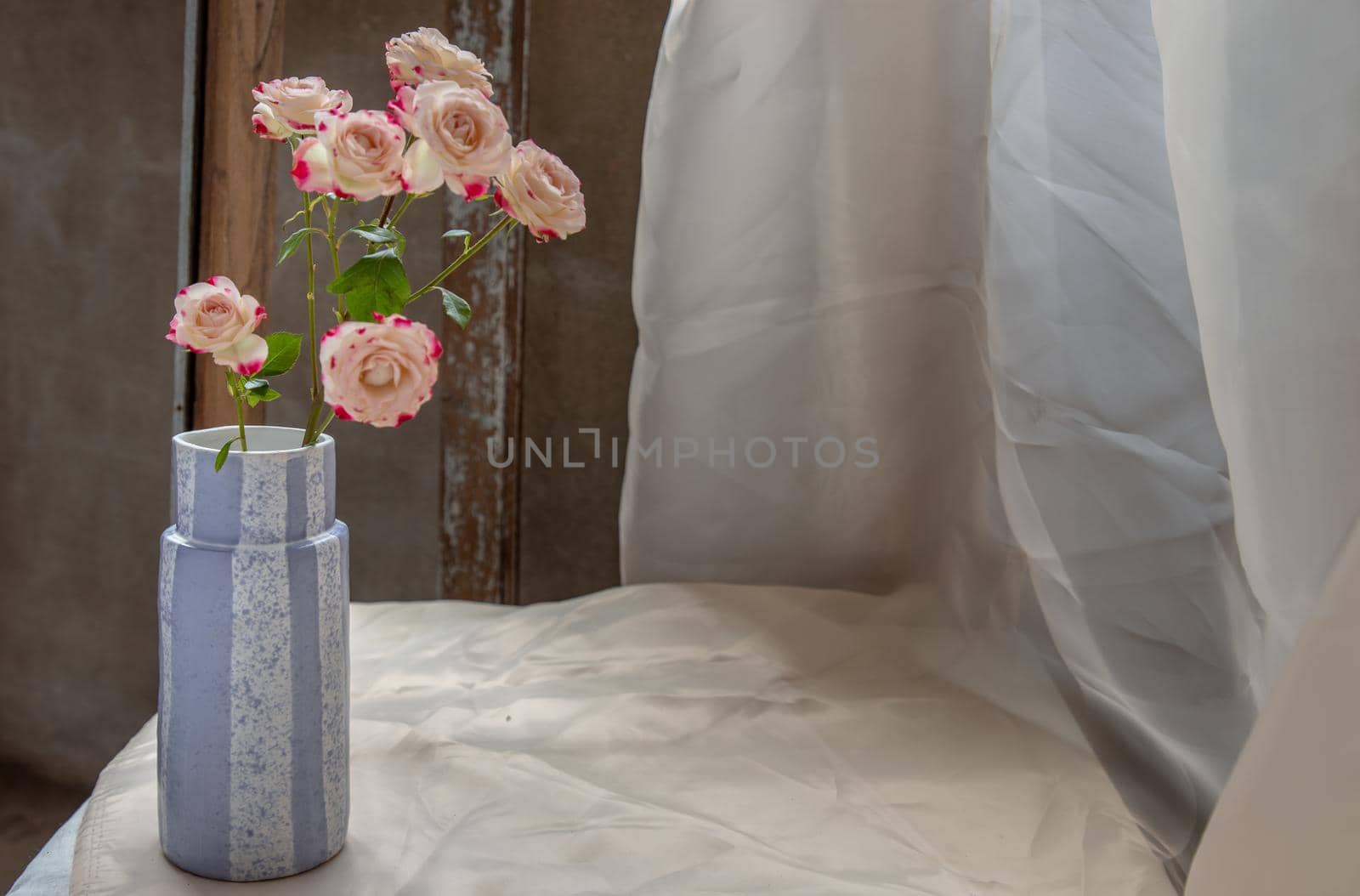 Bouquet of flowers in Blue handmade ceramic vase on Blush textured table cloth. Home decor, Copy space, Selective focus.