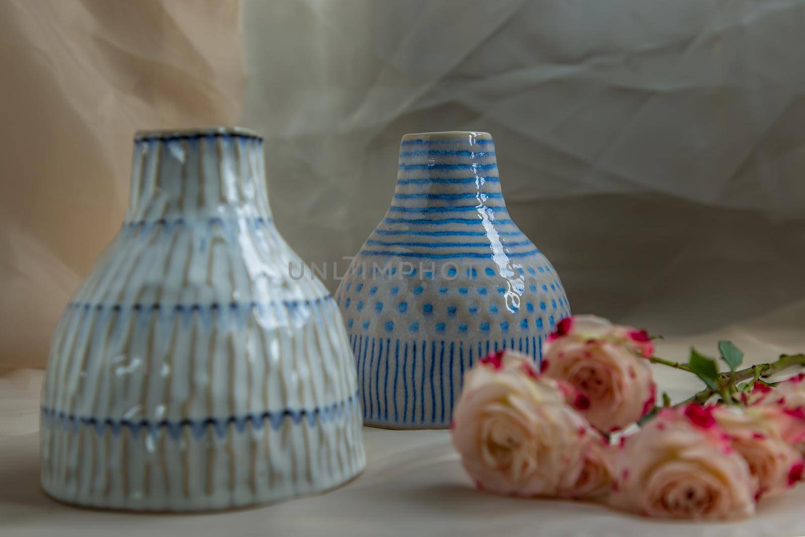 Two Blue and White handmade ceramic vase with Bouquet of flowers on Blush textured table cloth. Home decor, Copy space, Selective focus.