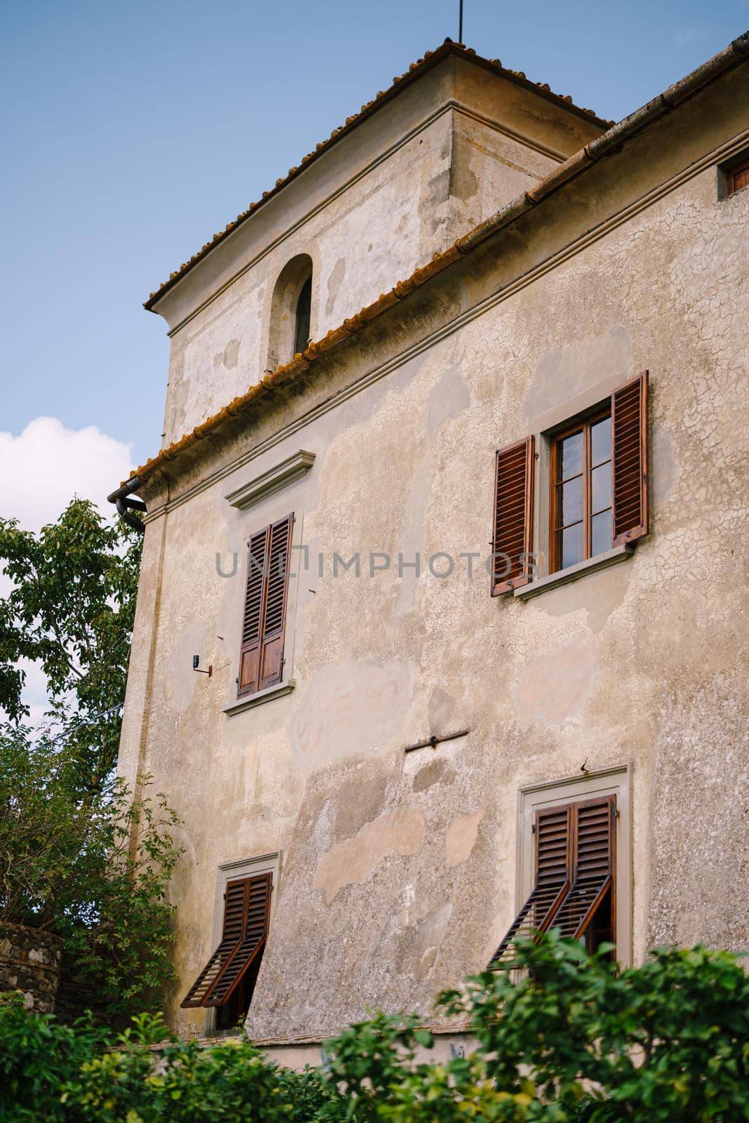 The facade of an old villa in Italy, in Florence. Stone staircase, windows with wooden shutters.