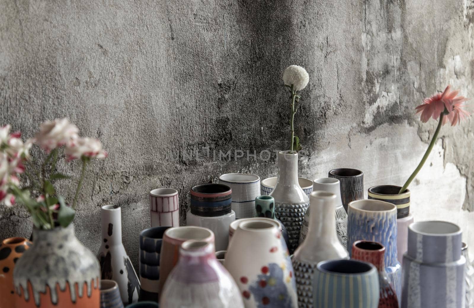 Bouquet of flowers in Handmade Assorted Many Different Ceramic Vases with old cement wall. Home decor. Selective focus.