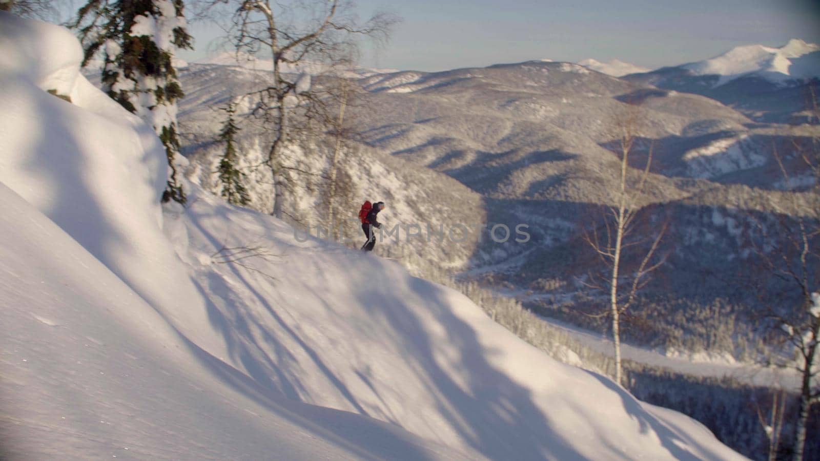A man riding down the hill in a snowy forest, side view. Freeride in Siberia.
