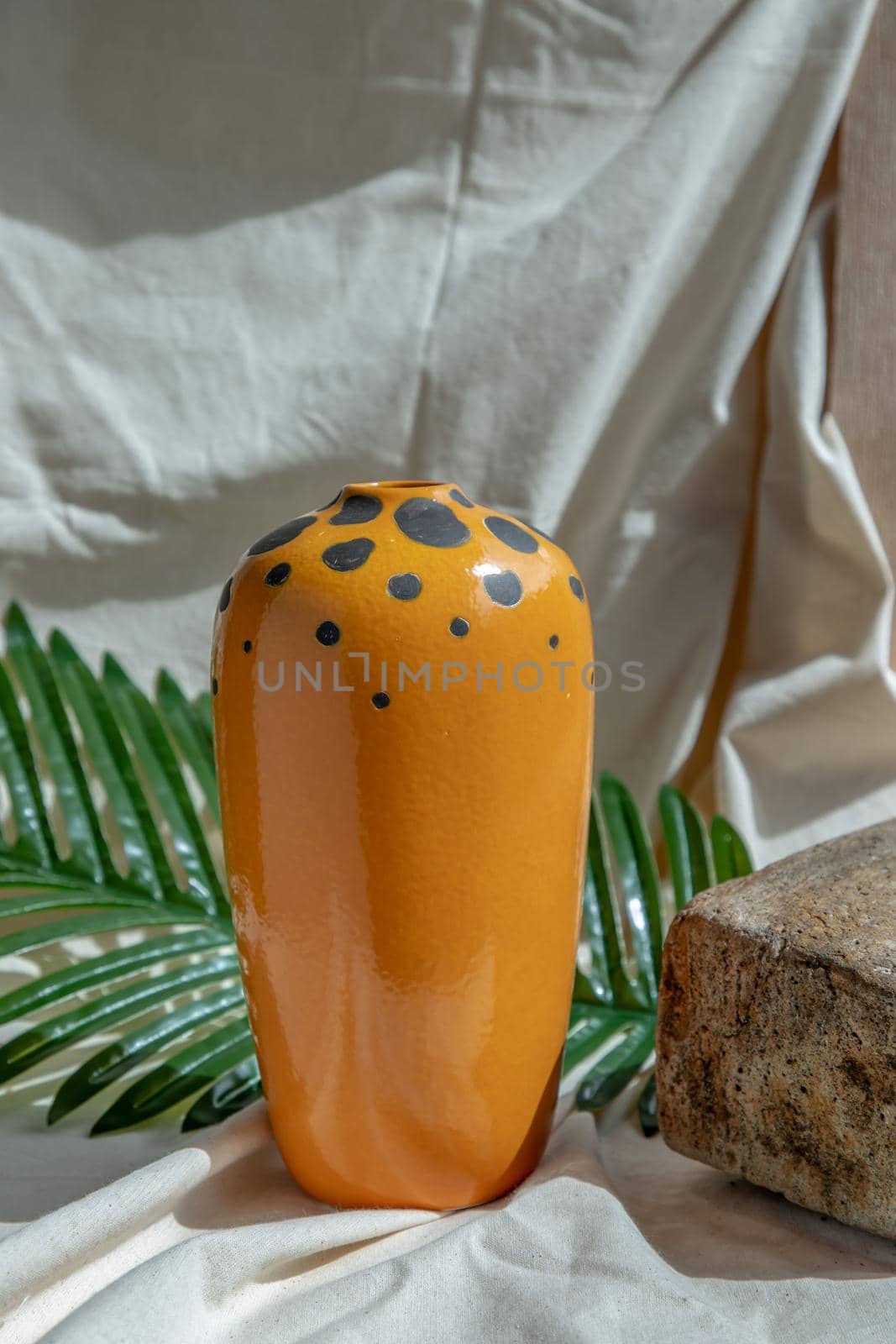Orange handmade ceramic vase on white textured table cloth. Home decor, Copy space, Selective focus.