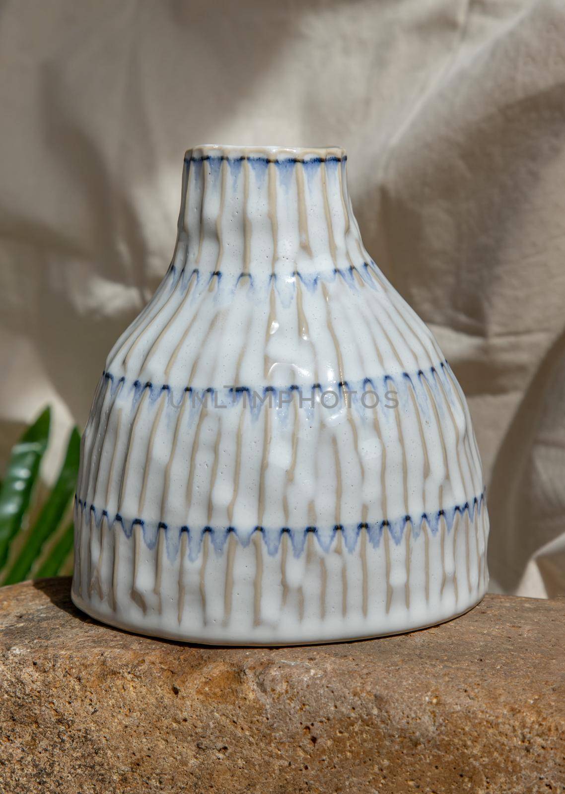 White handmade ceramic vase on white textured table cloth.  Home decor, Copy space, Selective focus.