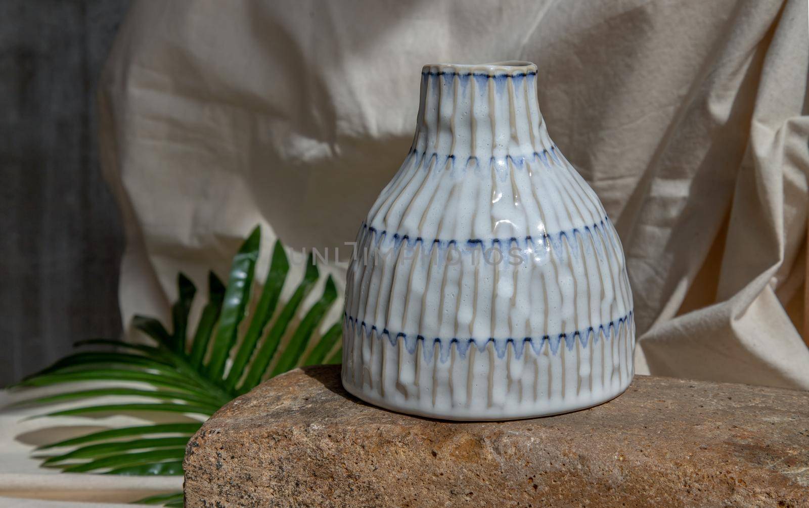 White handmade ceramic vase on white textured table cloth.  Home decor, Copy space, Selective focus.