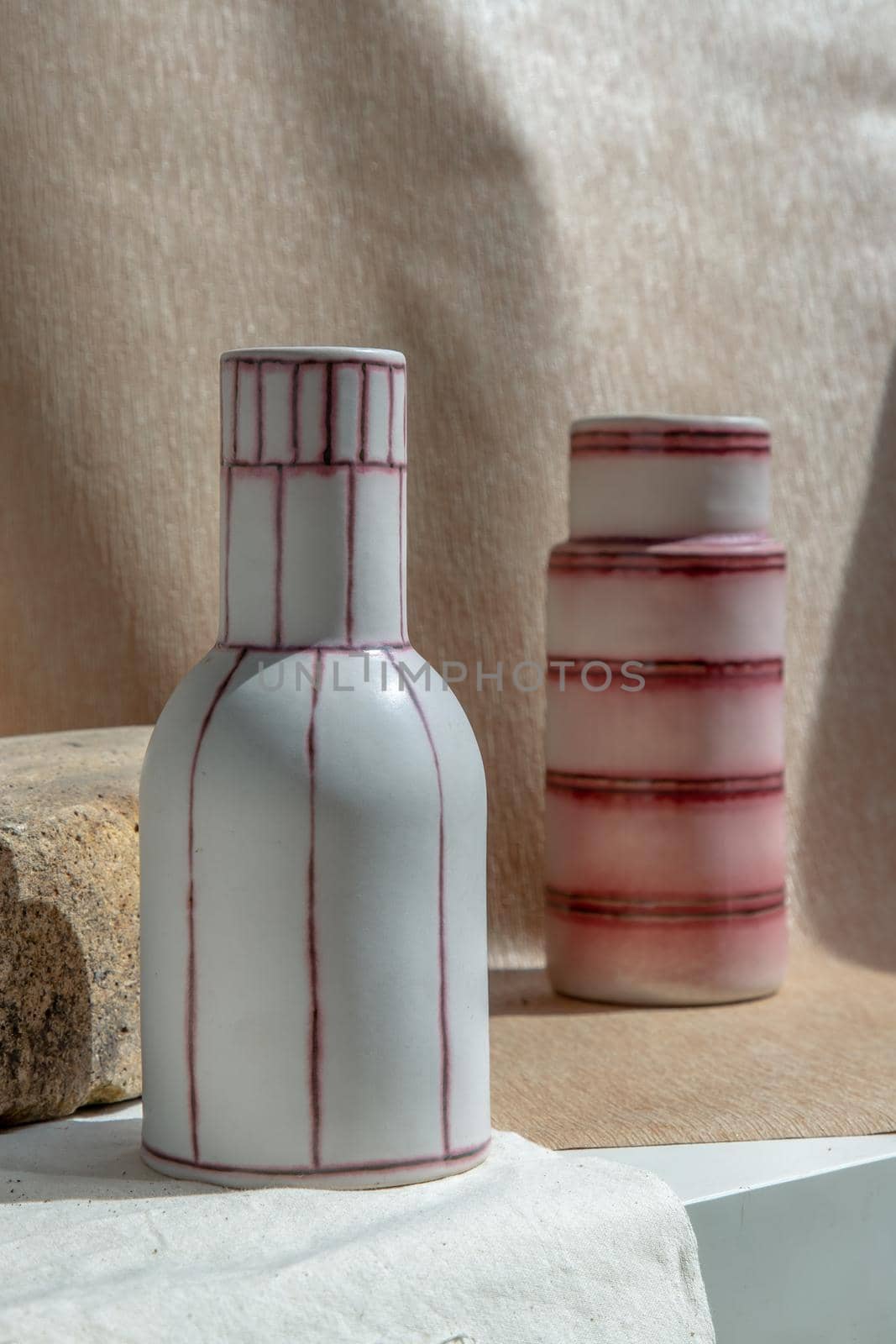 Two white and pink handmade ceramic vases on white textured table cloth.  Home decor, Copy space, Selective focus.