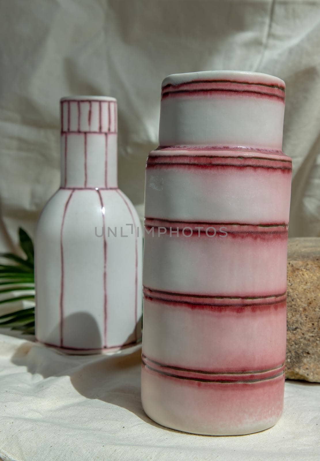 Two white and pink handmade ceramic vases on white textured table cloth.  Home decor, Copy space, Selective focus.