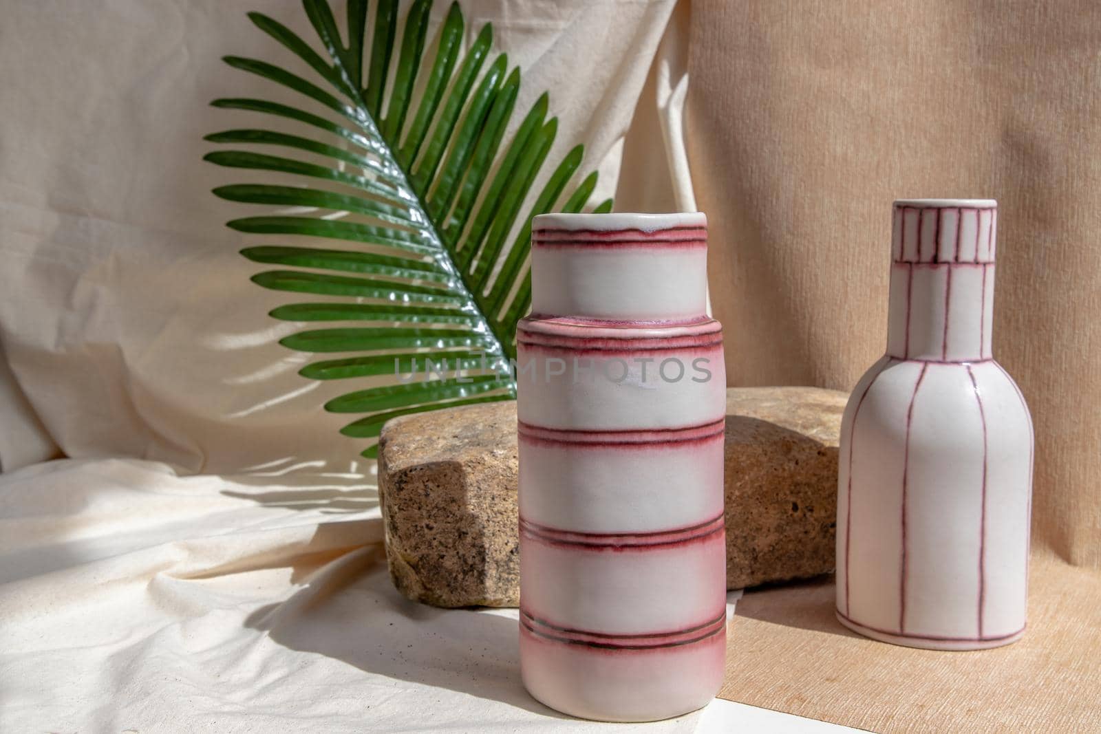 Two white and pink handmade ceramic vases on white textured table cloth.  Home decor, Copy space, Selective focus.