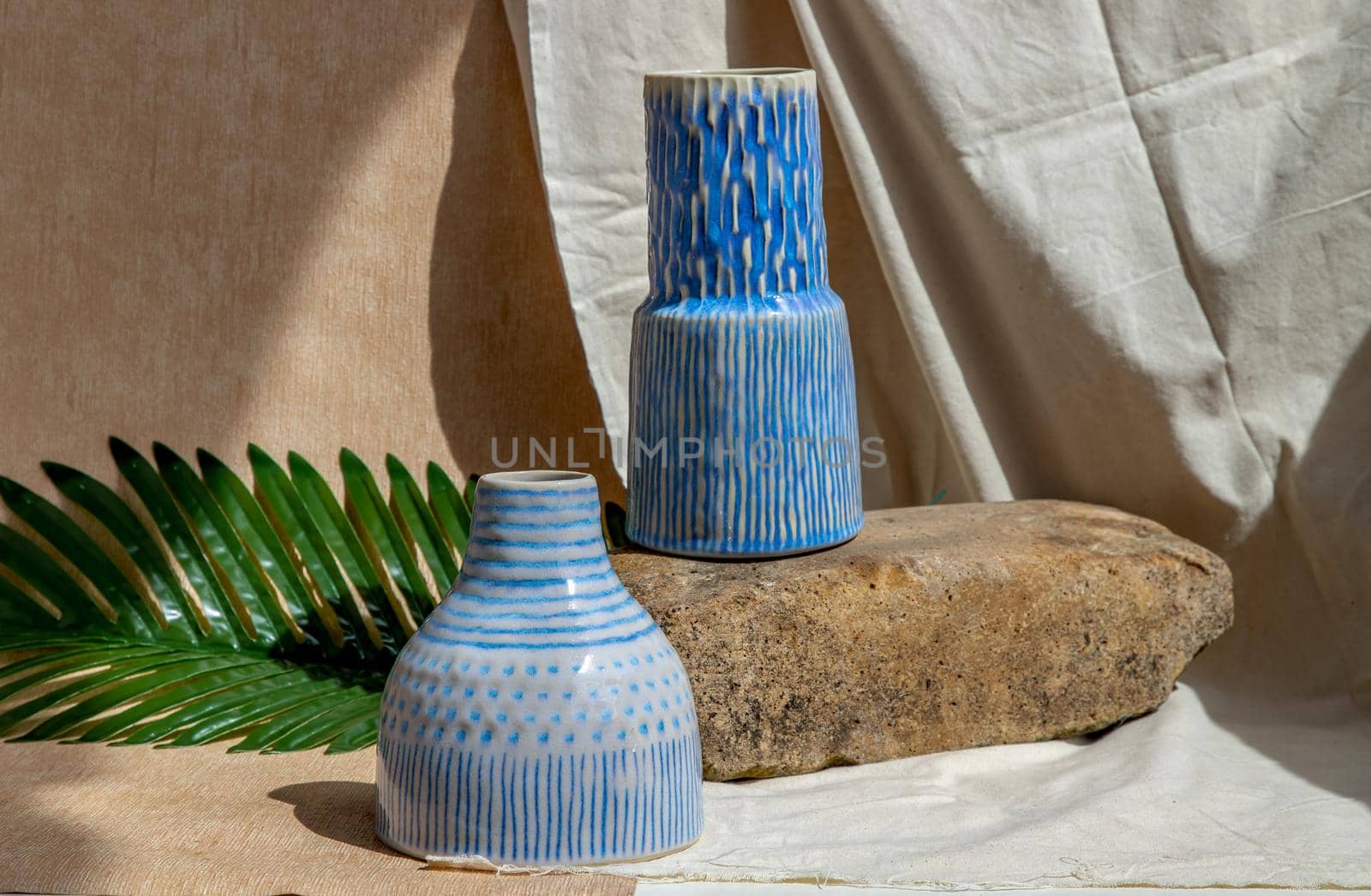 Two white and blue handmade ceramic vases on white textured table cloth.  Home decor, Copy space, Selective focus.