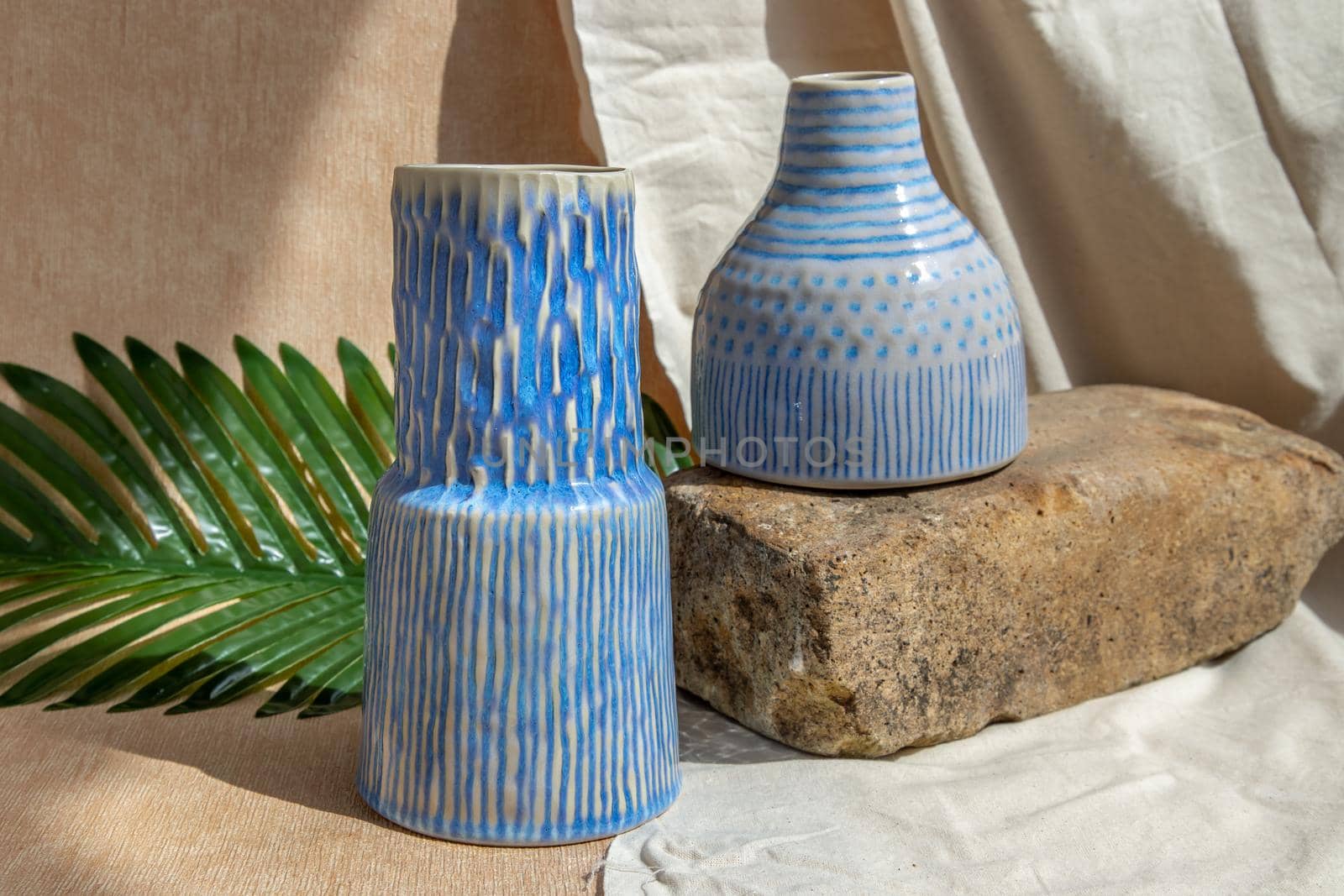 Two white and blue handmade ceramic vases on white textured table cloth.  Home decor, Copy space, Selective focus.
