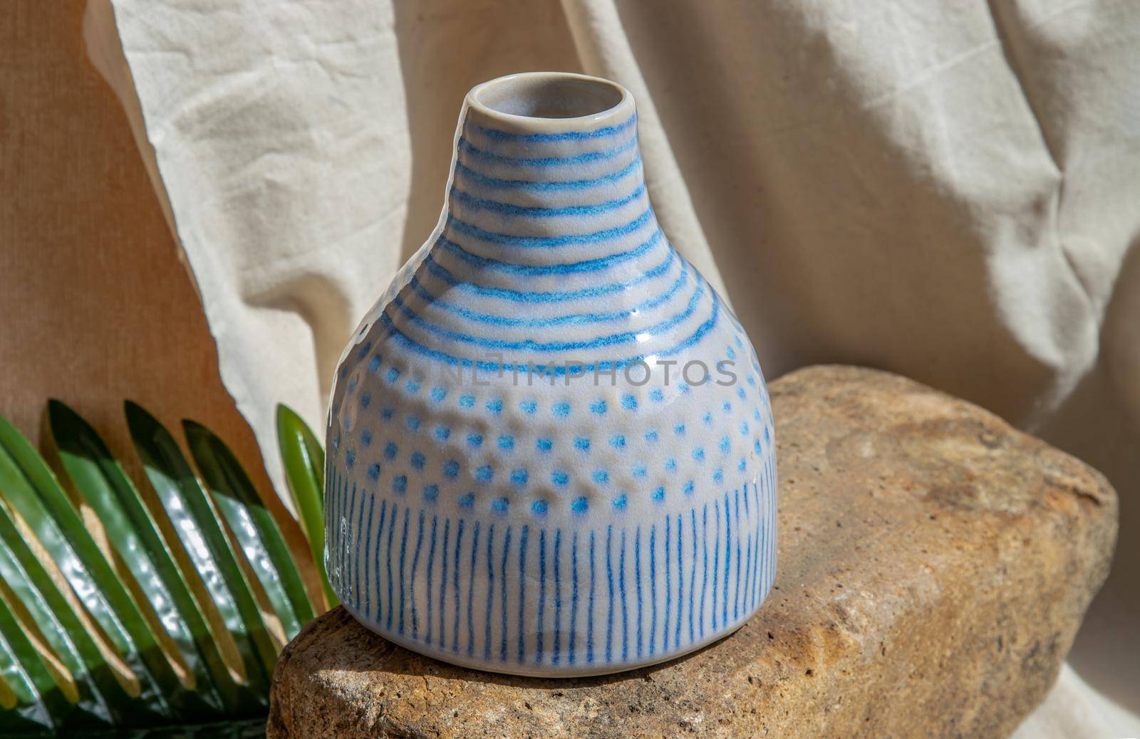 White and Blue handmade ceramic vase on white textured table cloth.  Home decor, Copy space, Selective focus.