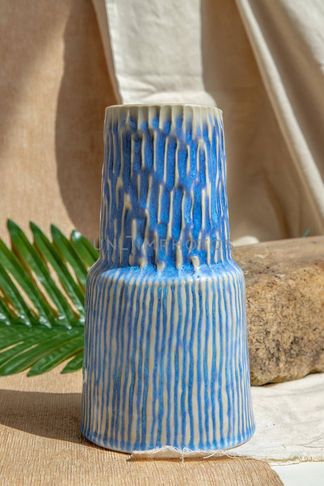 White and Blue handmade ceramic vase on white textured table cloth.  Home decor, Copy space, Selective focus.