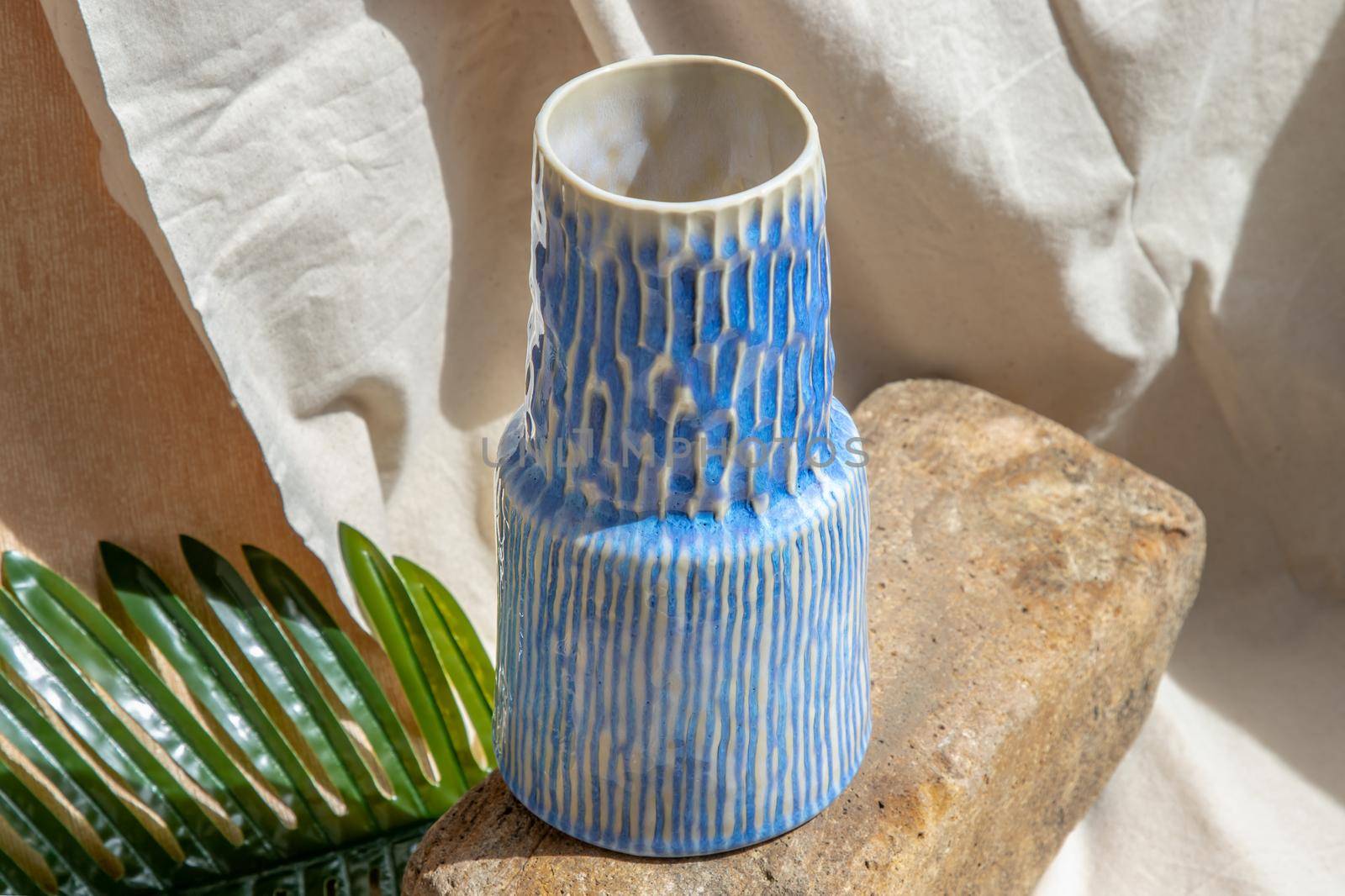White and Blue handmade ceramic vase on white textured table cloth.  Home decor, Copy space, Selective focus.