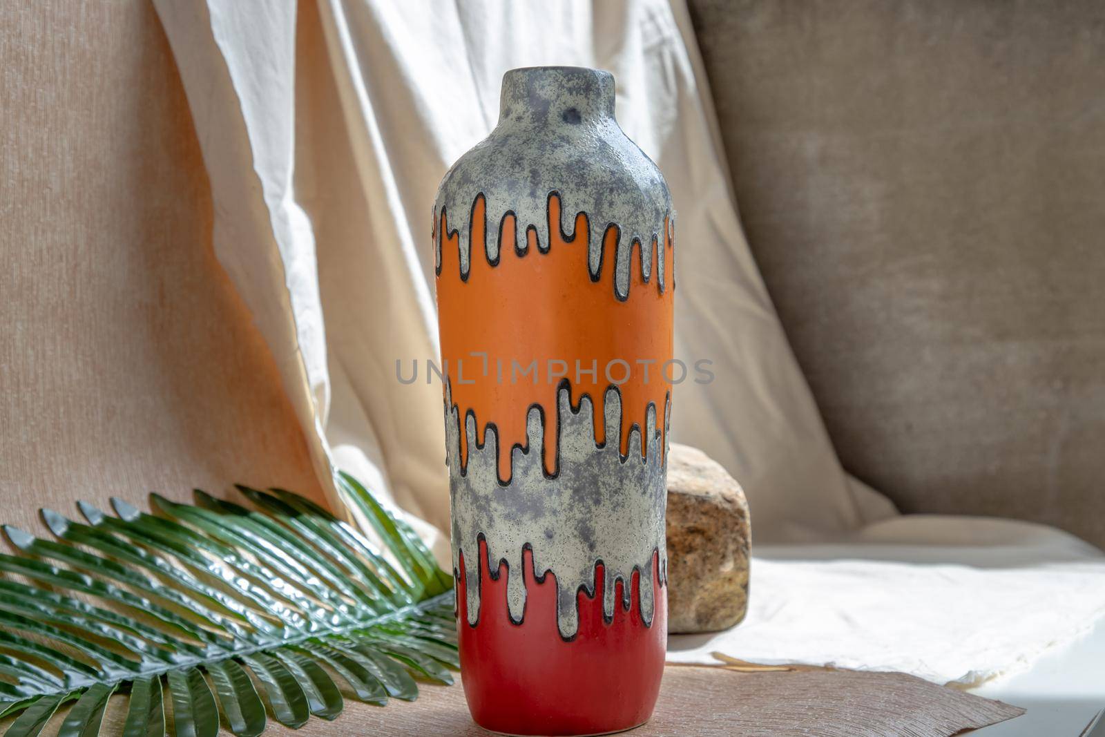 Orange and Red handmade ceramic vase on white textured table cloth.  Home decor, Copy space, Selective focus.