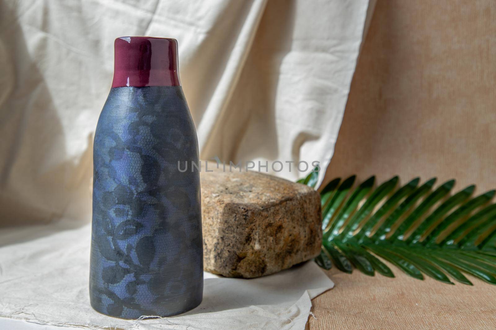 Blue and Crimson  handmade ceramic vase on white textured table cloth.  Home decor, Copy space, Selective focus.