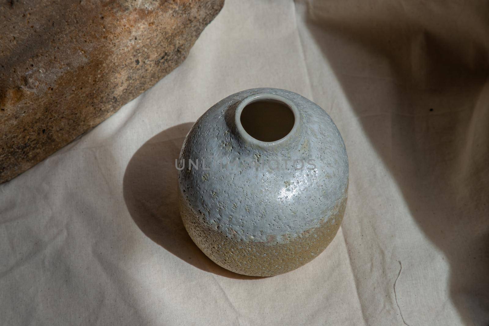 White and Yellow handmade ceramic vase on white textured table cloth. Home decor, Copy space, Selective focus.
