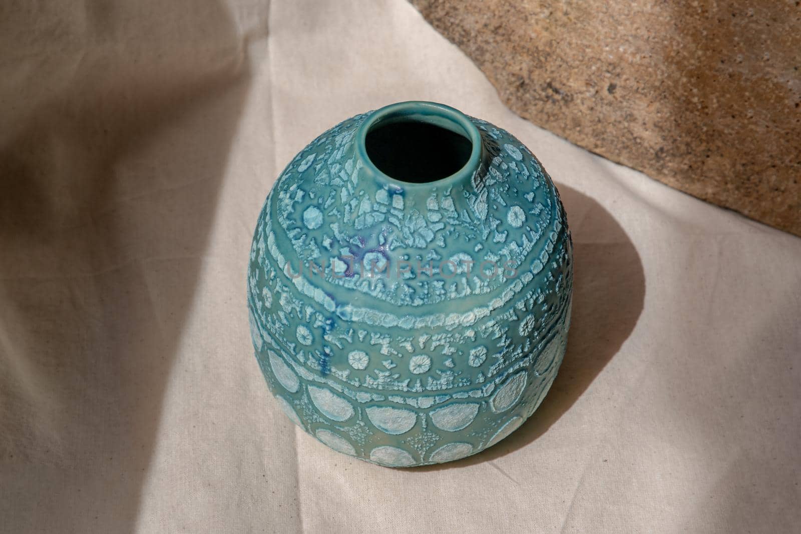 Blue handmade ceramic vase on white textured table cloth. Home decor, Copy space, Selective focus.