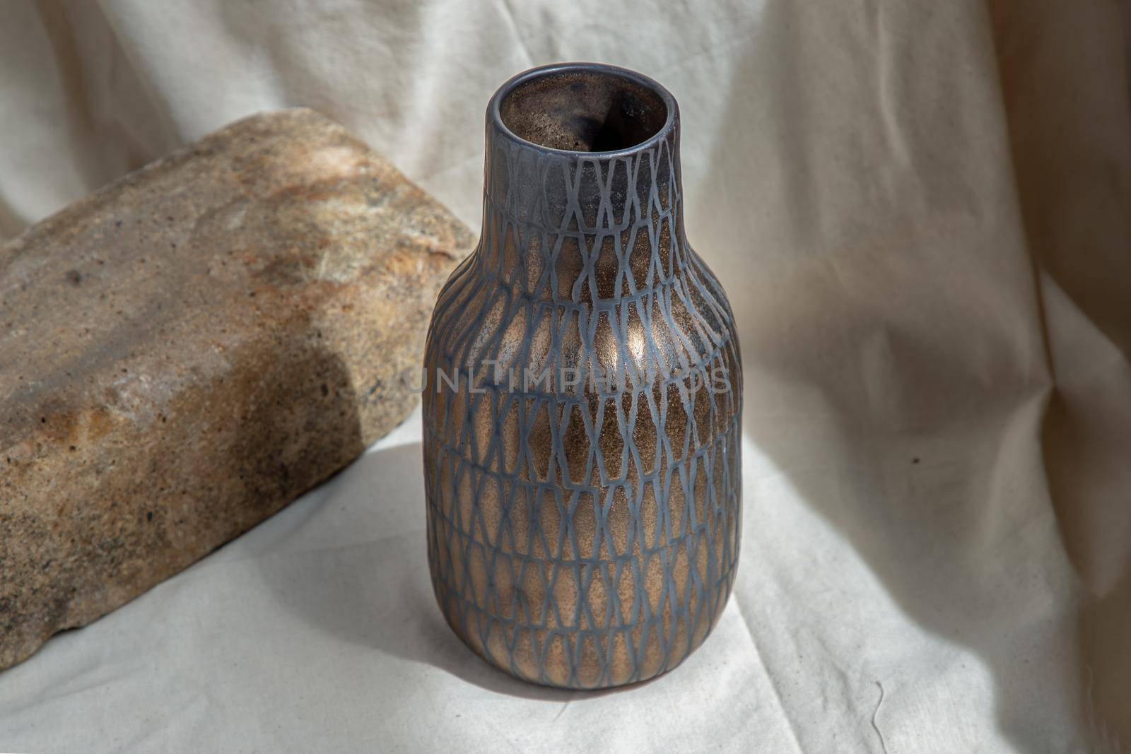 Copper color handmade ceramic vase on white textured table cloth. Home decor, Copy space, Selective focus.