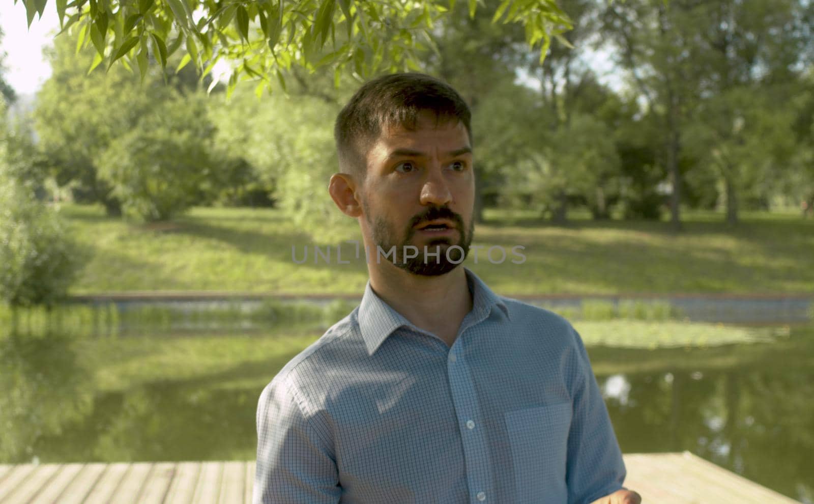 Portrait of talking man against lake and park