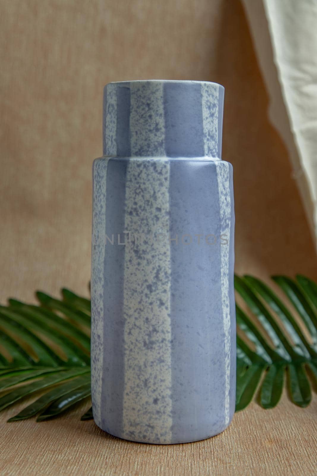Blue handmade ceramic vase on white textured table cloth. Home decor, Copy space, Selective focus.