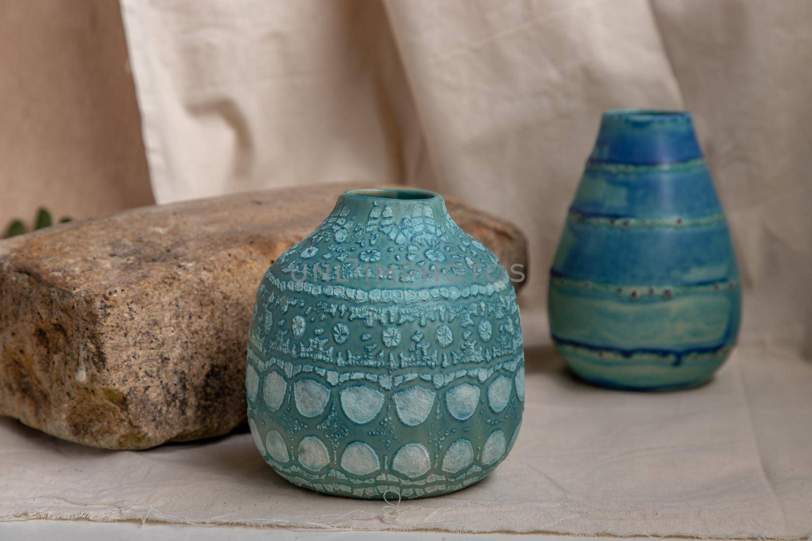 Two blue handmade ceramic vases on white textured table cloth. Home decor, Copy space, Selective focus.