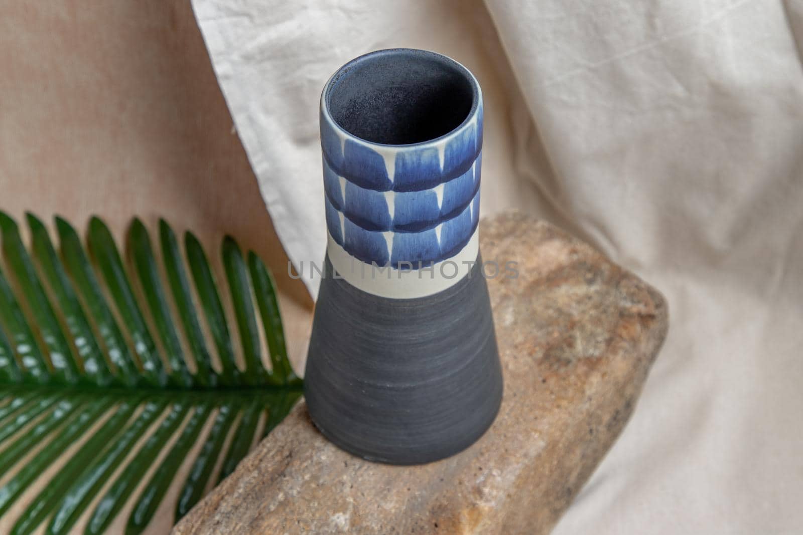 Blue handmade ceramic vase on white textured table cloth. Home decor, Copy space, Selective focus.