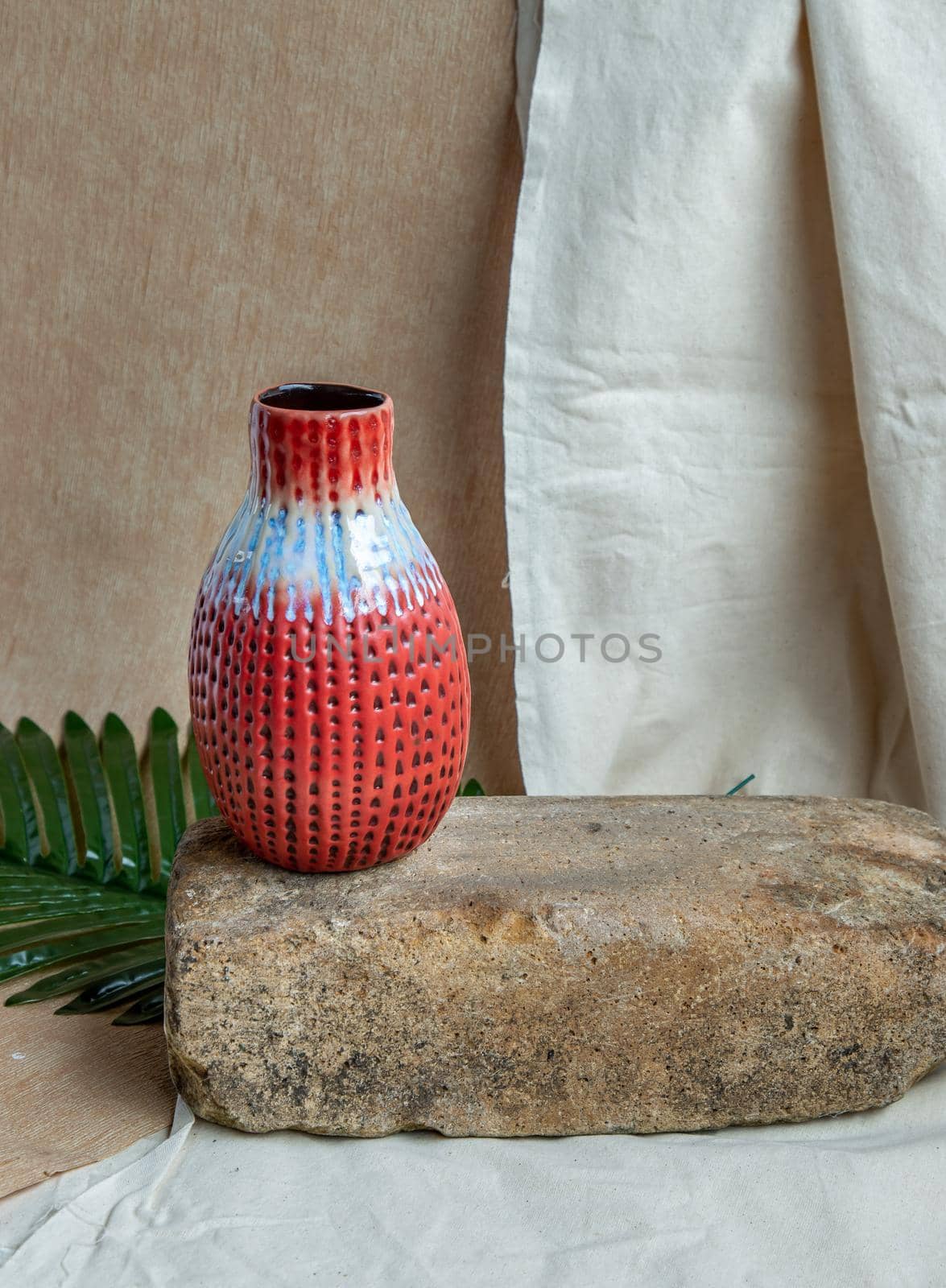 Red handmade ceramic vase on white textured table cloth.  Home decor, Copy space, Selective focus.