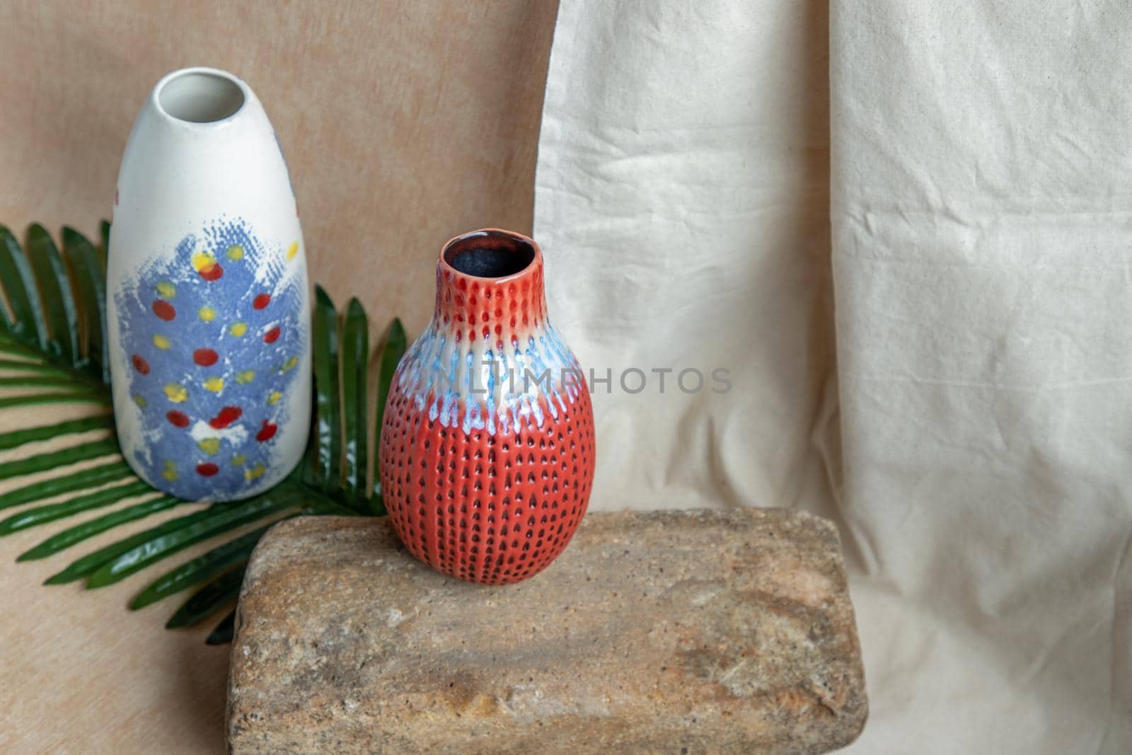 Two Blue and Red handmade ceramic vases on white textured table cloth. Home decor, Copy space, Selective focus.