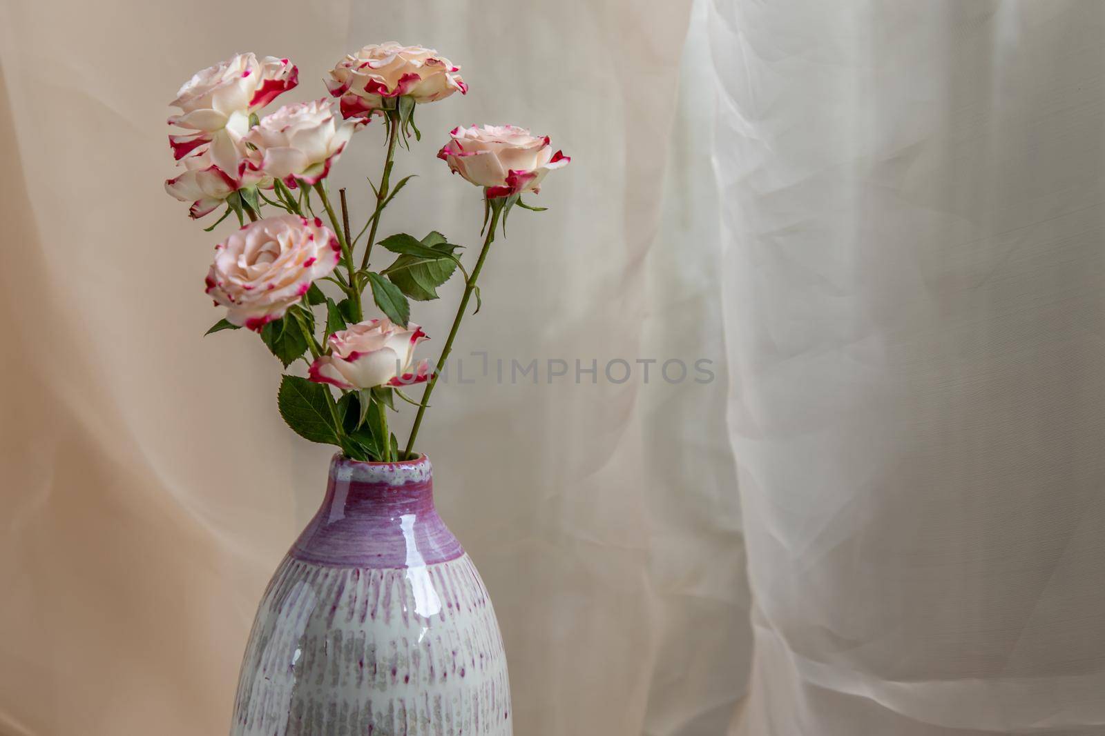 Close-up of Bouquet of flower in Purple and White handmade ceramic vase on Blush textured table cloth. Home decor, Copy space, Selective focus.