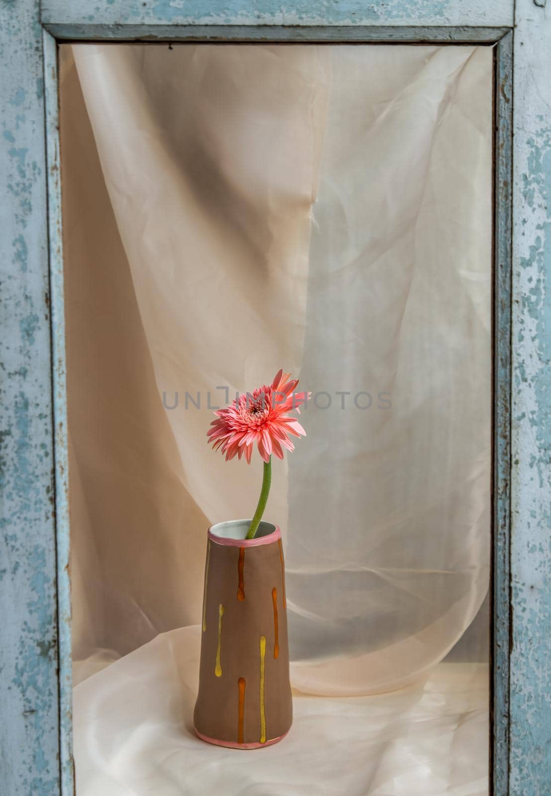 Pink flower in Brown handmade ceramic vase on Blush textured table cloth. Home decor, Copy space, Selective focus.