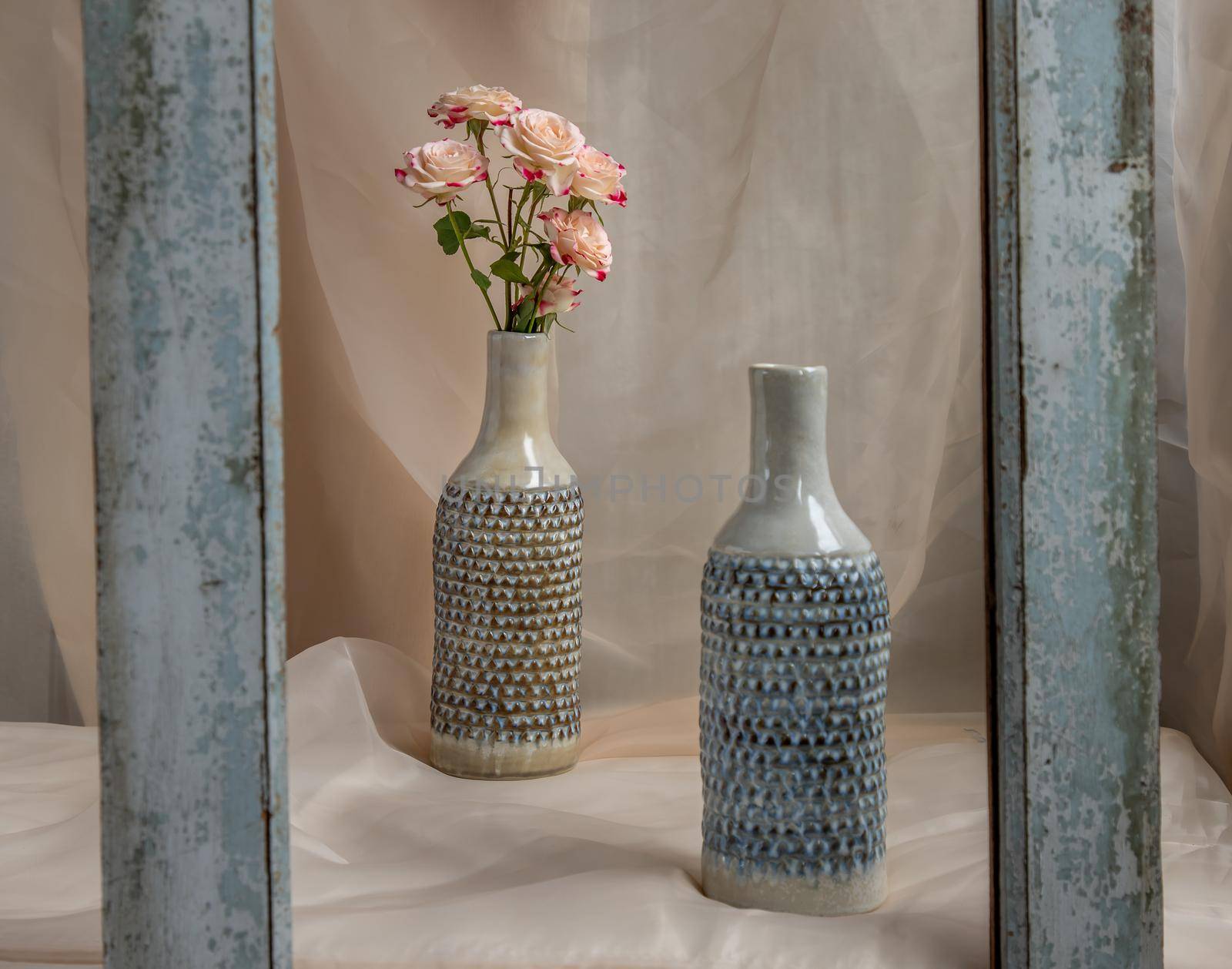 Bouquet of Pink flowers in Blue handmade ceramic vases in Wooden frame on Blush textured table cloth. Home decor, Copy space, Selective focus.