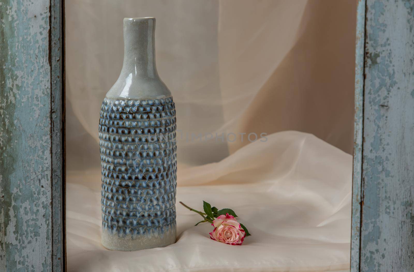 Blue handmade ceramic vase with flower on Blush textured table cloth.  Home decor, Copy space, Selective focus.
