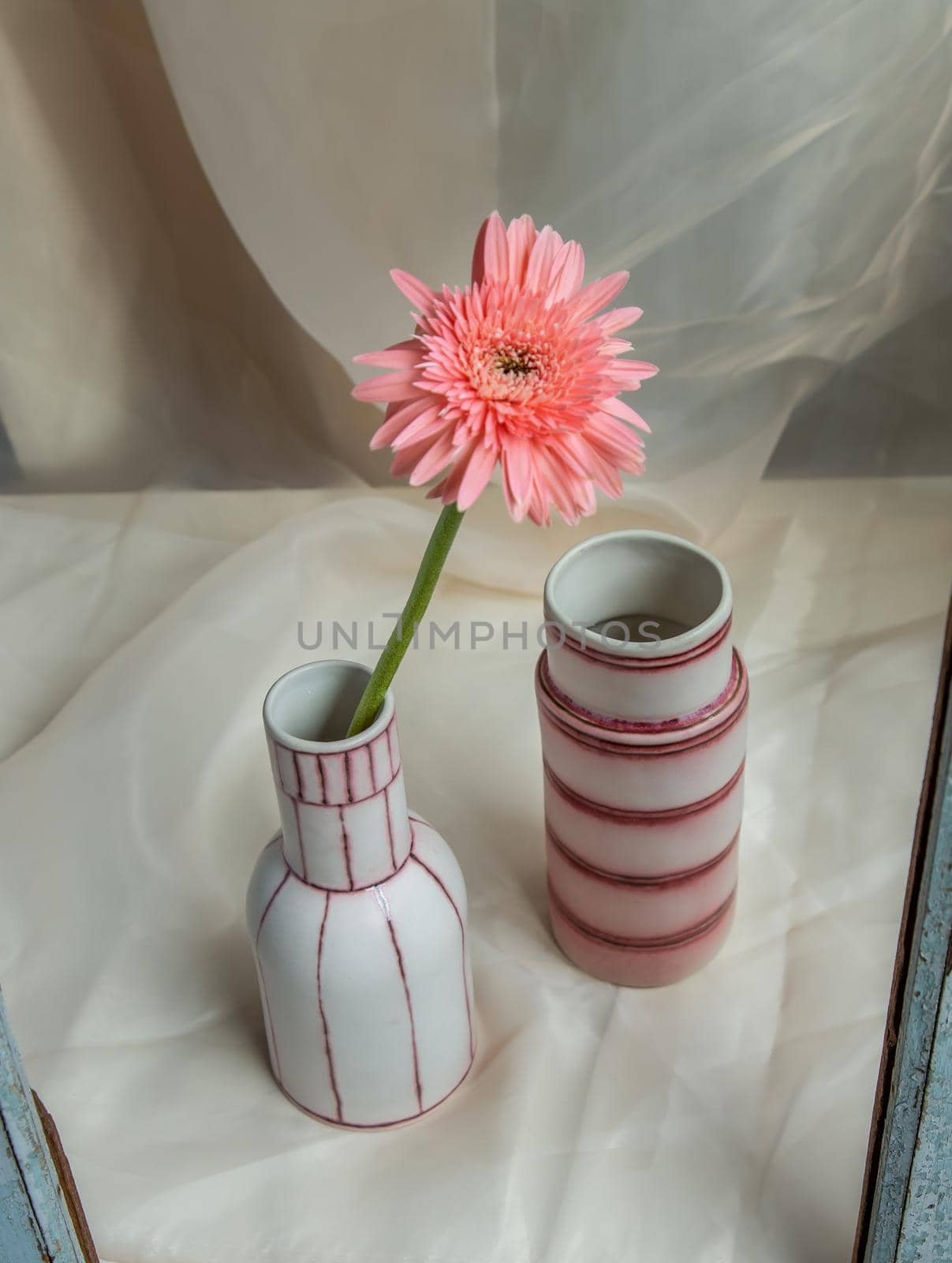 Pink flower in White and Pink handmade ceramic vases on Blush textured table cloth. Home decor, Copy space, Selective focus.