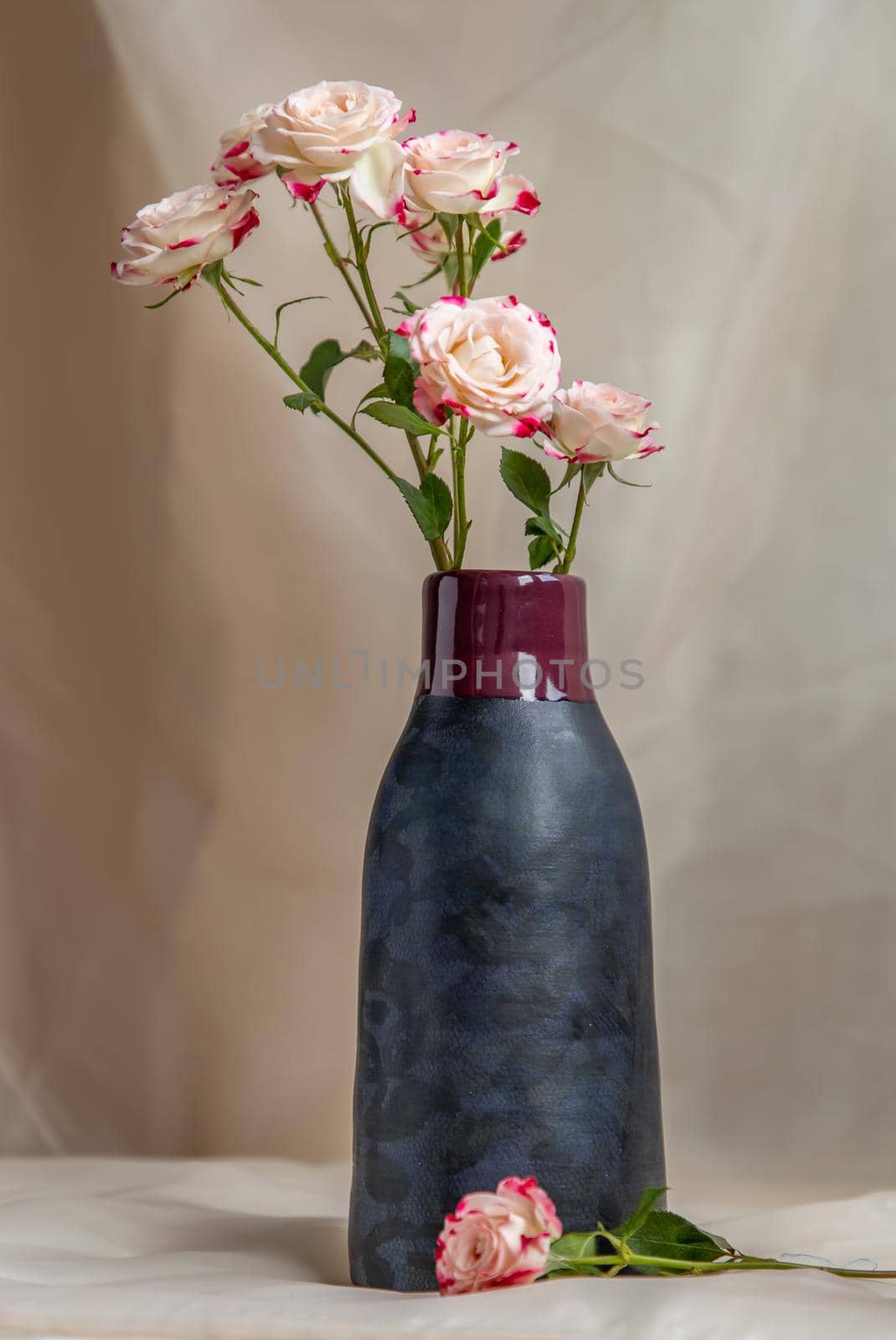Bouquet of flower in Blue handmade ceramic vase on Blush textured table cloth. Home decor, Copy space, Selective focus.