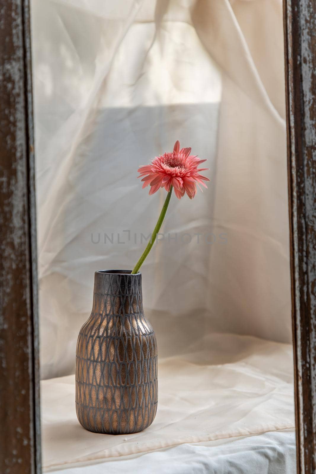 Pink flower in Copper color handmade ceramic vase and on Blush textured table cloth. Home decor, Copy space, Selective focus.