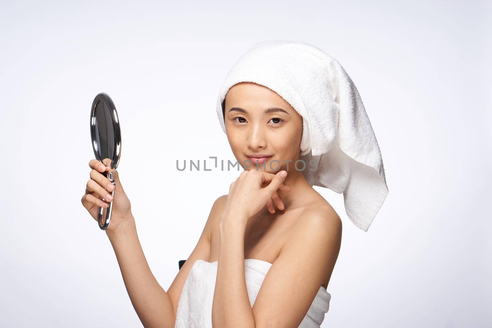 pretty asian woman in the mirror in trousers towel on head rejuvenation clear skin. High quality photo