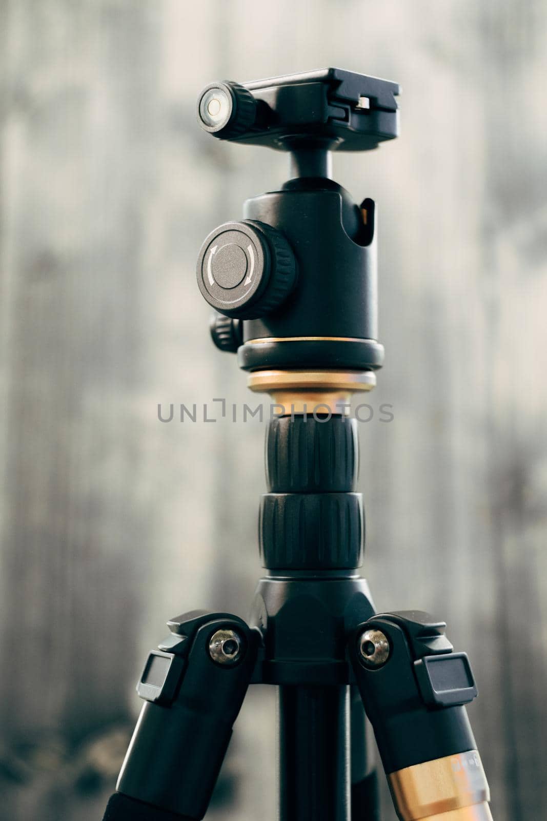 A small unbreakable black photo tripod on a gray wooden background