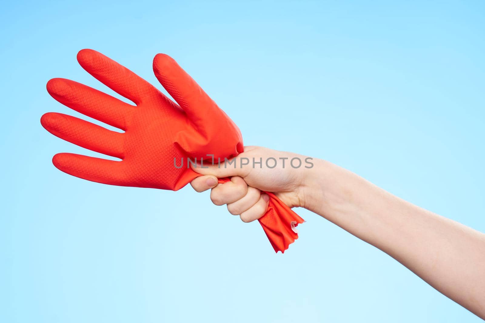inflated rubber red glove in hand blue background and house cleaning. High quality photo