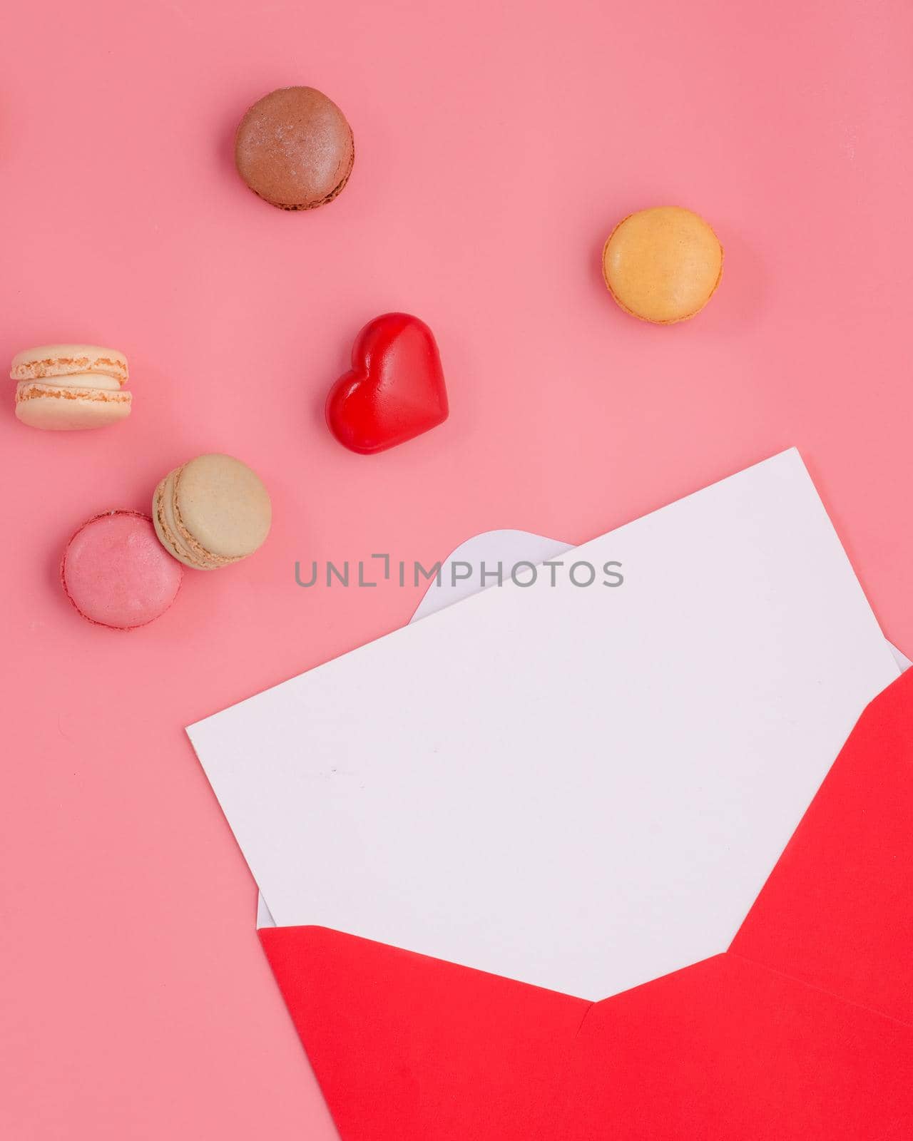 open envelope with empty blank, heart and macaroons on pink background